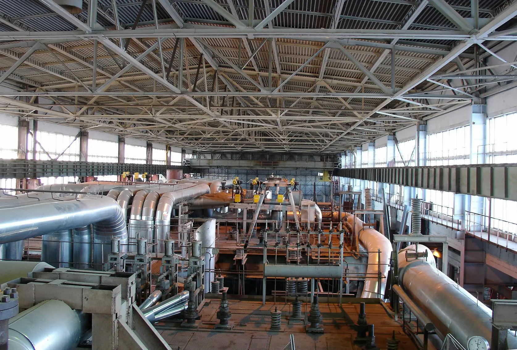 A large warehouse with pipes and machinery in it.