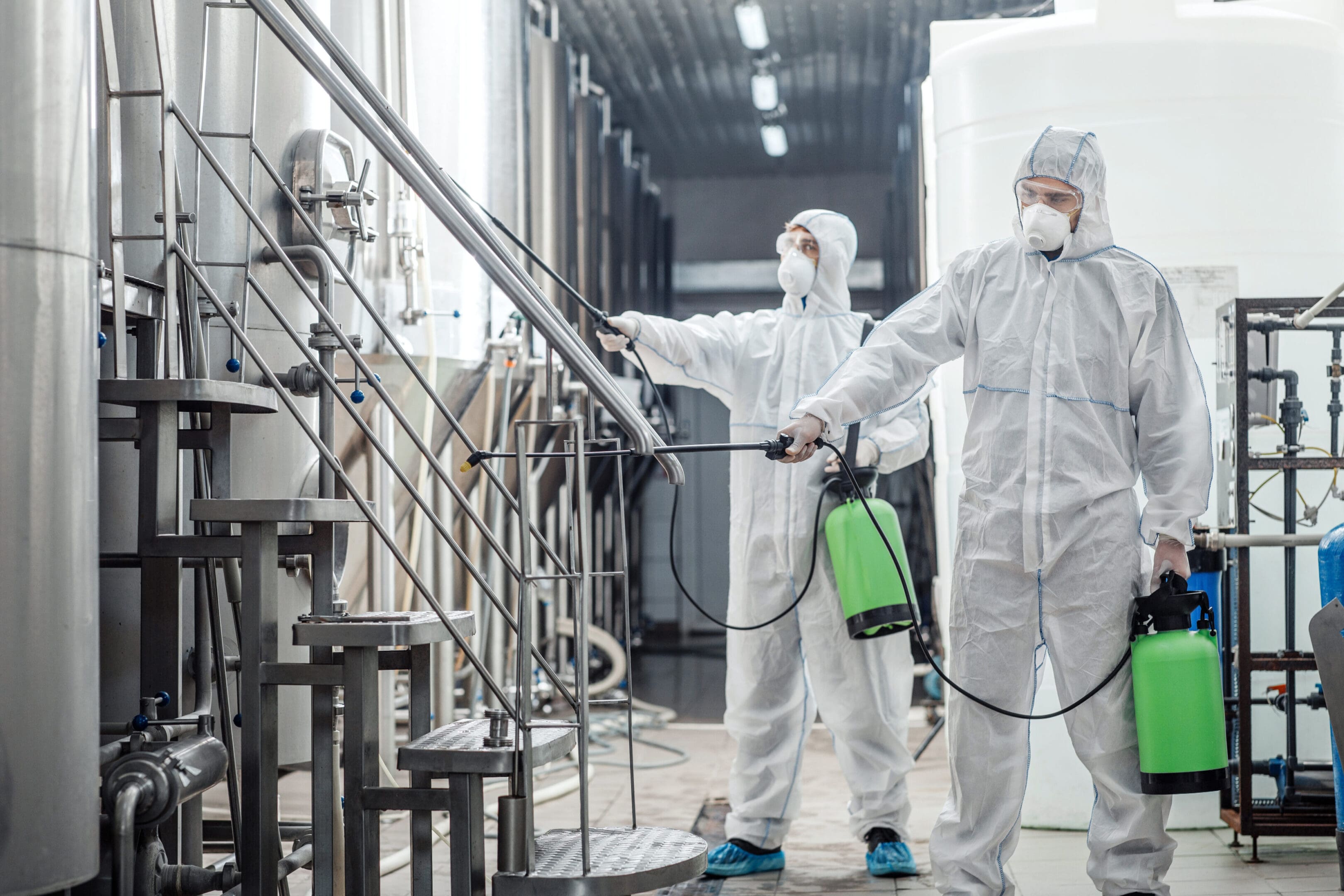 Two people in white suits spraying a staircase.