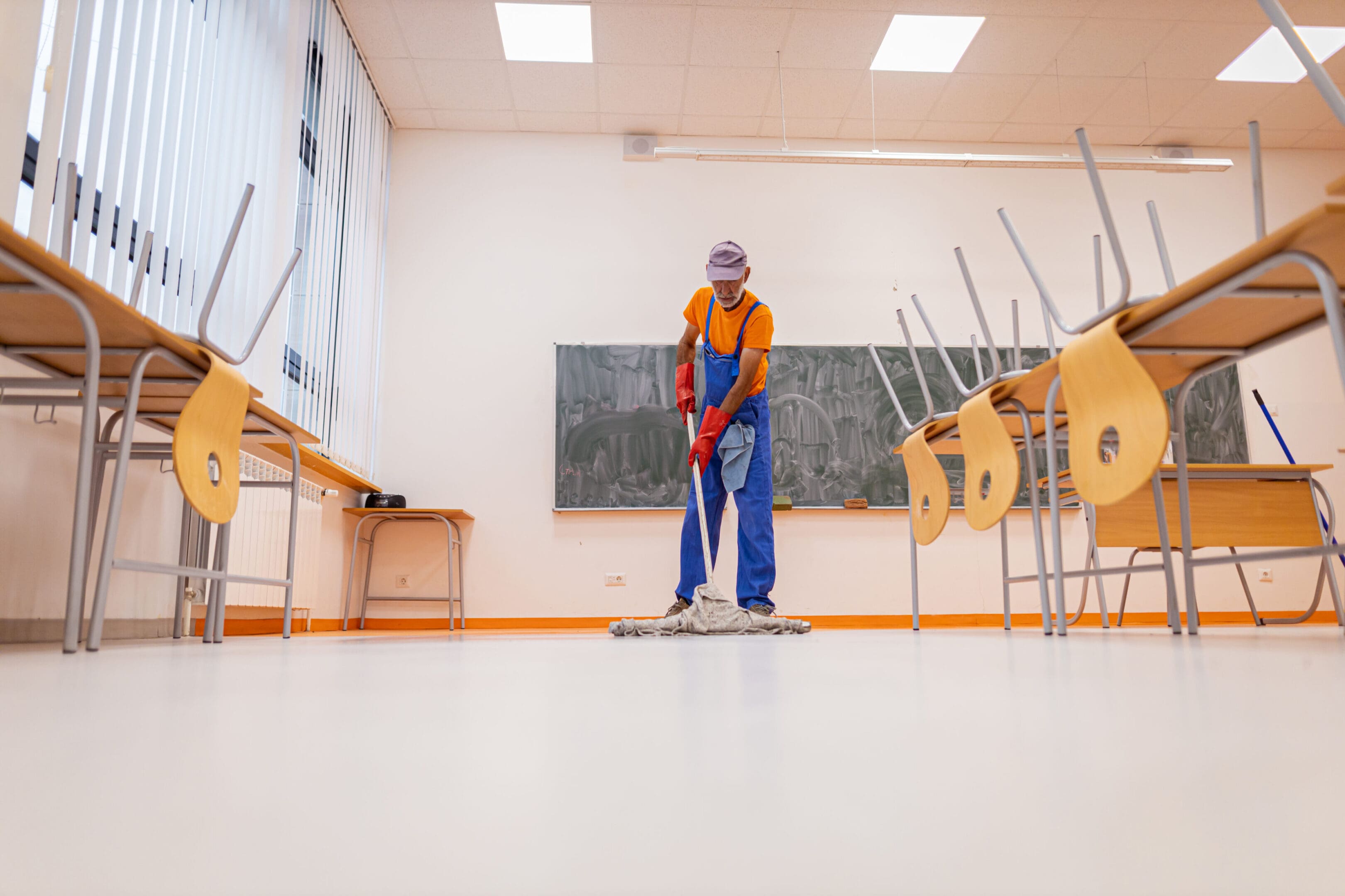 A man in an orange and blue suit is mopping the floor